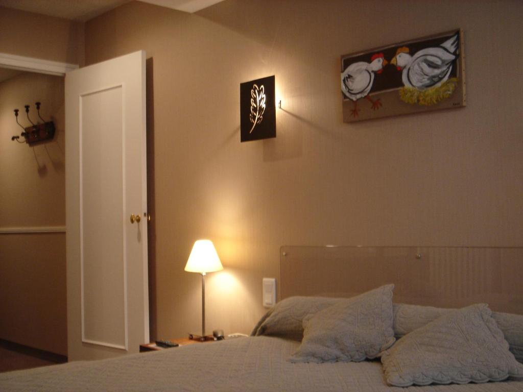 1 dormitorio con 1 cama con lámpara y una foto en la pared en Cit'Hotel des Messageries, en Saintes