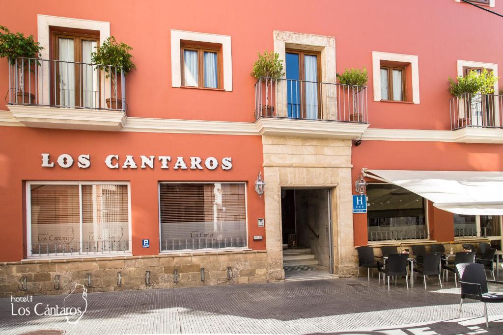 un edificio rojo con mesas y sillas delante de él en Los Cantaros, en El Puerto de Santa María