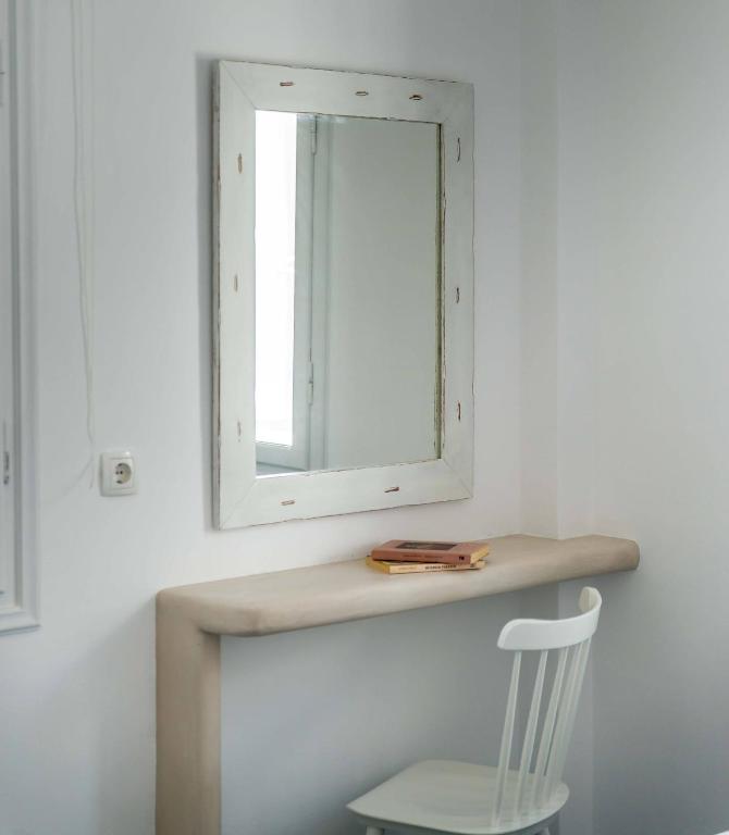 a mirror on a wall next to a chair at Michalakis Seaside Suites in Pollonia