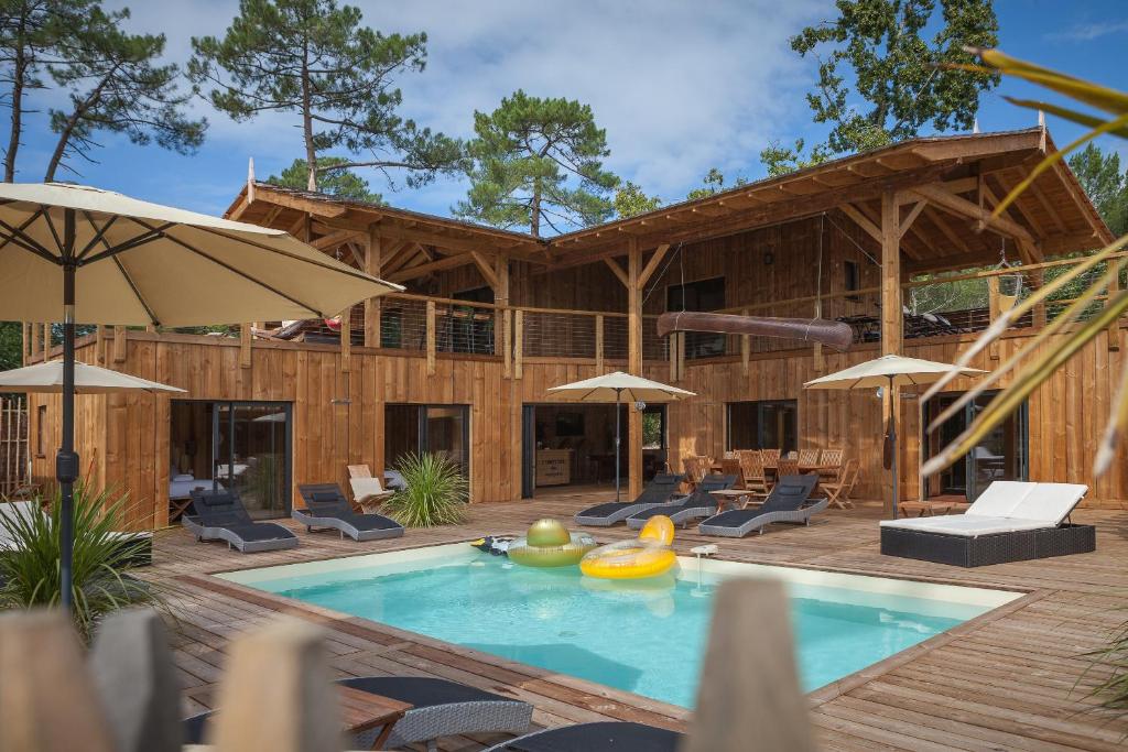 una casa con piscina con sillas y sombrillas en Ô Lac, en Lacanau