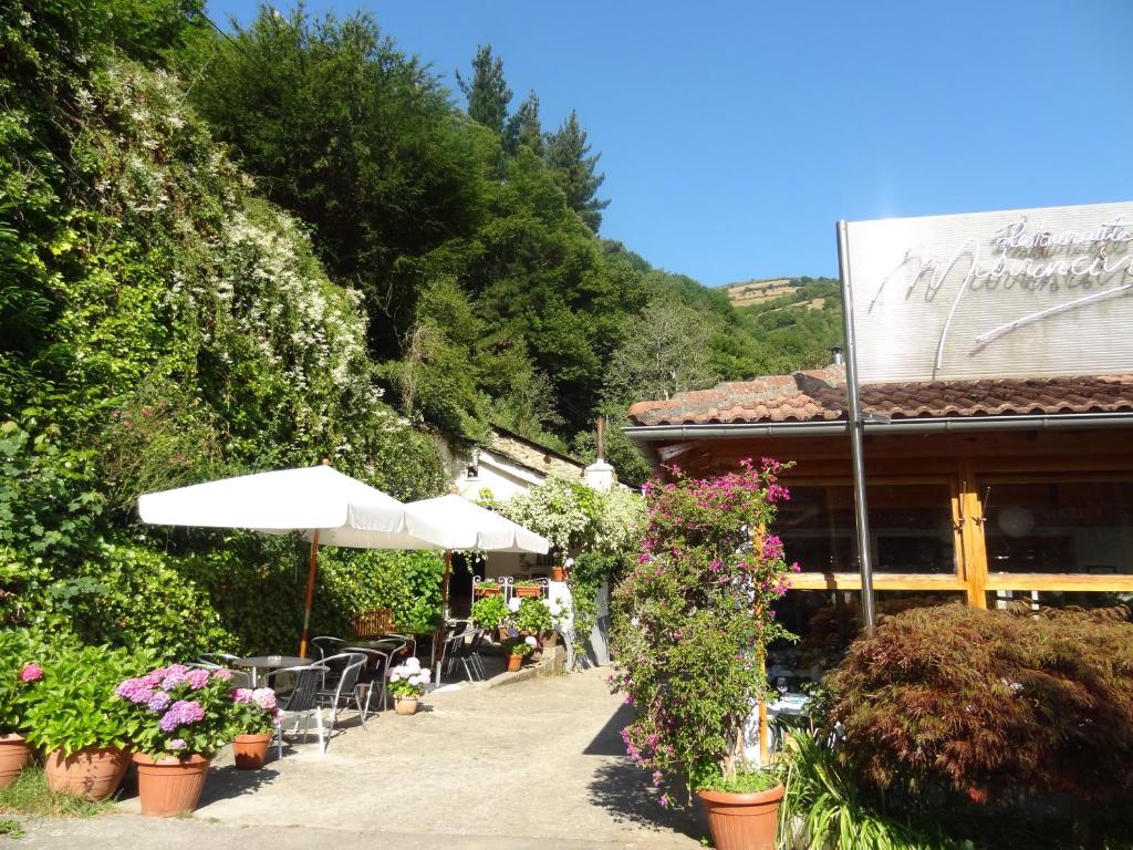 a patio with tables and umbrellas and flowers at Hotel Restaurante Marroncín in Cangas del Narcea