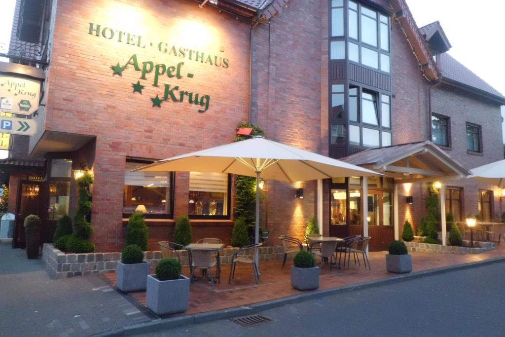 un restaurant avec des tables et des parasols en face d'un bâtiment dans l'établissement Hotel Gasthaus Appel Krug, à Delbrück