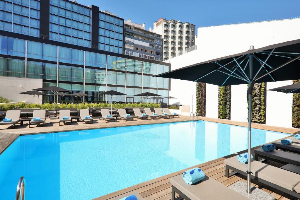 a swimming pool with chairs and umbrellas on a building at Iberostar Selection Lisboa in Lisbon