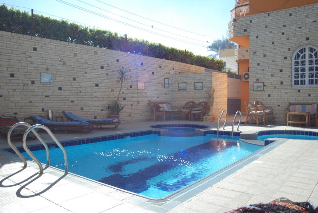 una piscina en un patio con una pared de ladrillo en Al Gezera Apartments, en Luxor