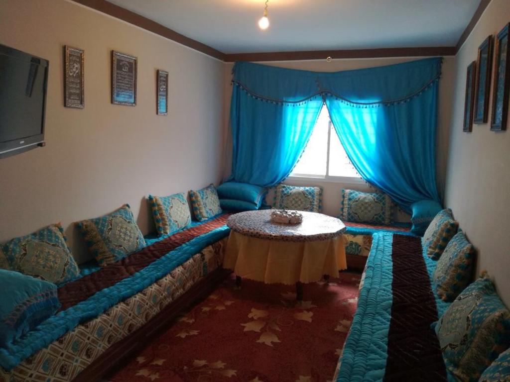 een woonkamer met een bank en een tafel bij Cozy Appartement in Douar Ben Chellal