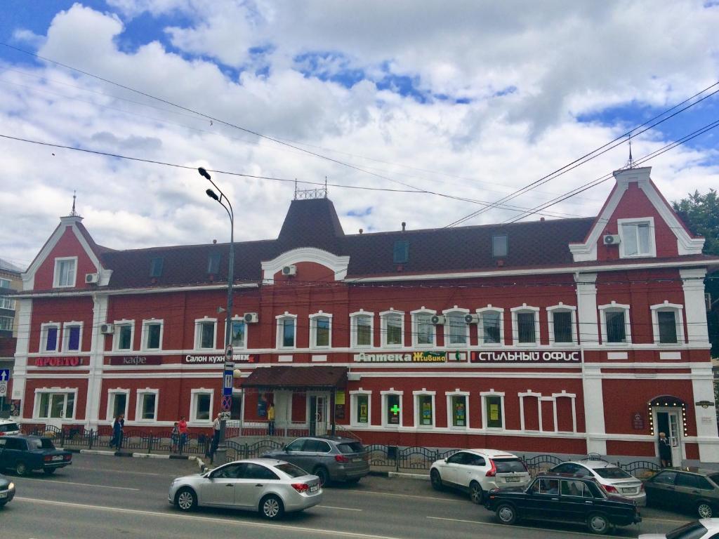 ein großes rotes Gebäude mit davor geparkt in der Unterkunft Старый Город in Sergijew Possad