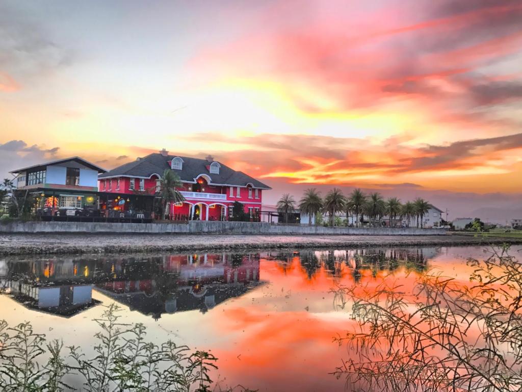 a house on the shore of a lake at sunset at MiCarro B&amp;B in Dongshan