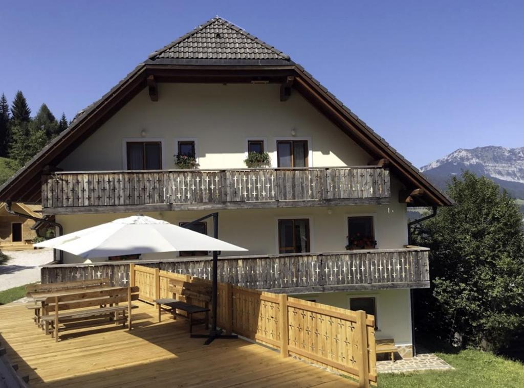 a house with a deck and an umbrella at Kmetija Matk in Solčava