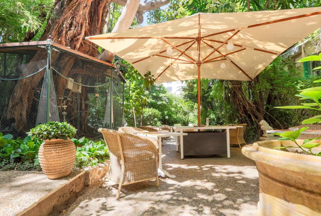 a patio with a table and an umbrella at Le Windsor, Jungle Art Hotel in Nice