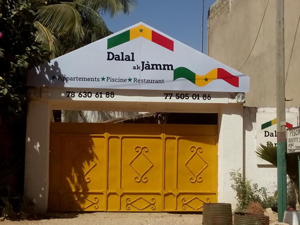 een gele garagedeur met een bord erop bij Guesthouse Dalal ak Jàmm in Mbour