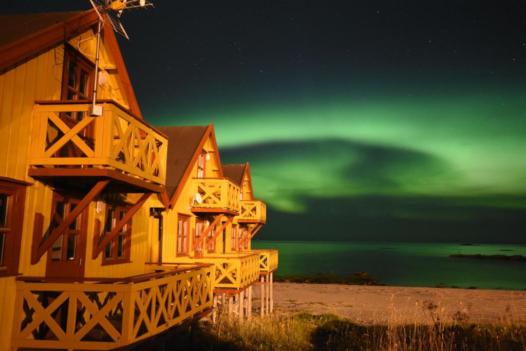 un grupo de casas bajo la verde aurora boreal en Bleik Sea Cabins, en Bleik