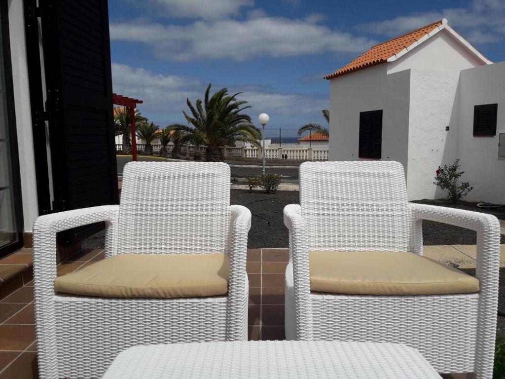 dwa białe krzesła siedzące na balkonie w obiekcie Sun Luz Apartments 84 w mieście Caleta De Fuste