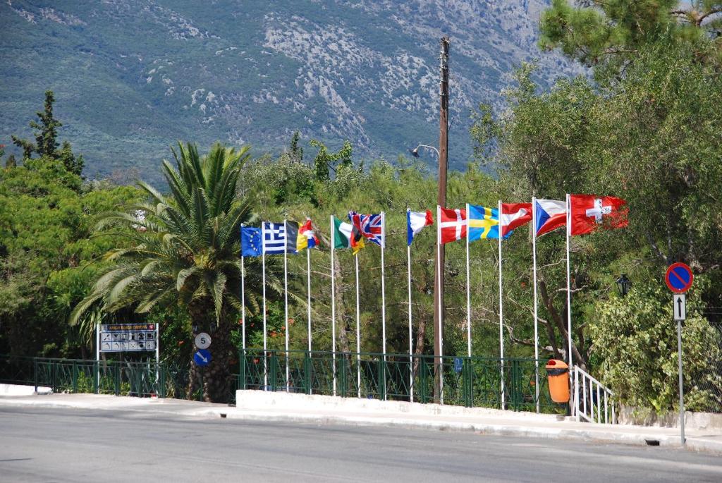a bunch of flags on a fence next to a road at Happy Camp mobile homes in Karda Beach Camping in Corfu Town