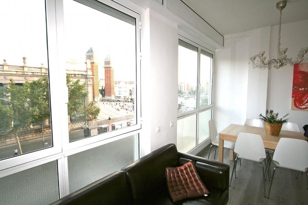 a living room with a couch and a table and windows at ApartEasy - Plaza España Deluxe in Barcelona