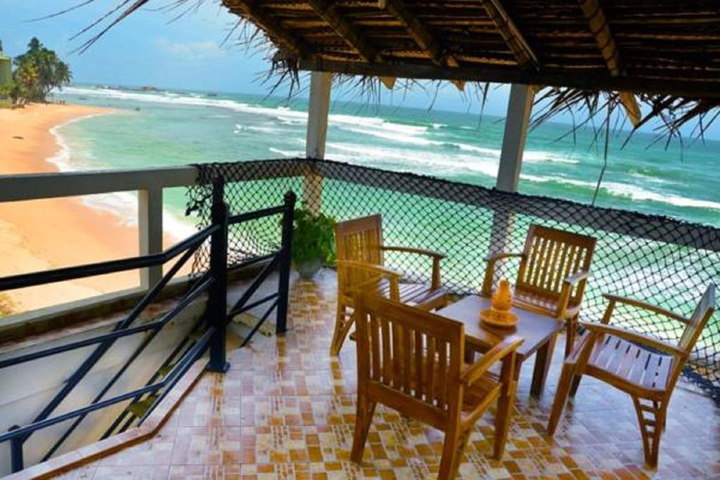a table and chairs on a balcony with the beach at Happy Tuna Beach Apartment in Hikkaduwa