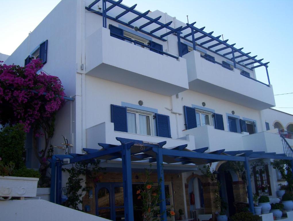 a white building with blue shutters and awning at Pelagia Beach Studios in Agia Pelagia