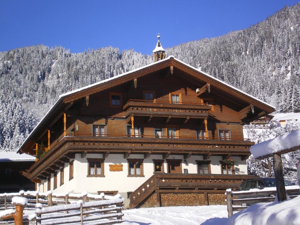 un grand bâtiment en bois avec de la neige au sol dans l'établissement Veitenhof, à Krimml