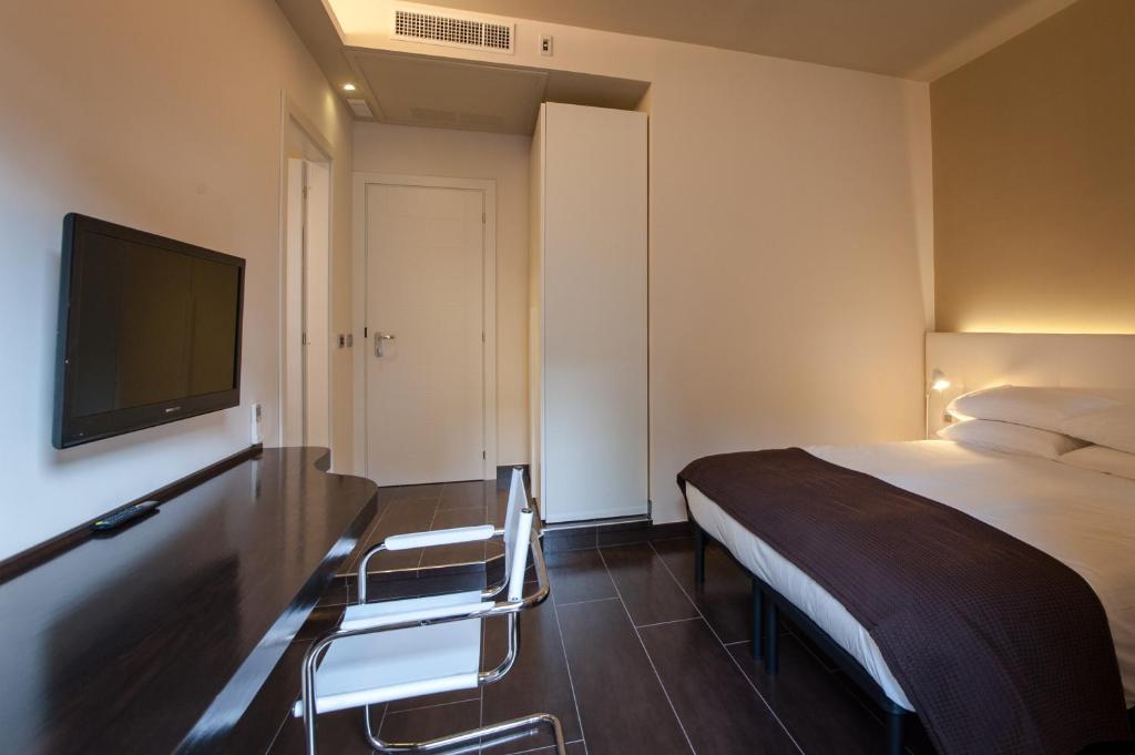 ローマにあるレジデンツァ タレンティ スーペリア ルームズのベッド1台、薄型テレビが備わるホテルルームです。