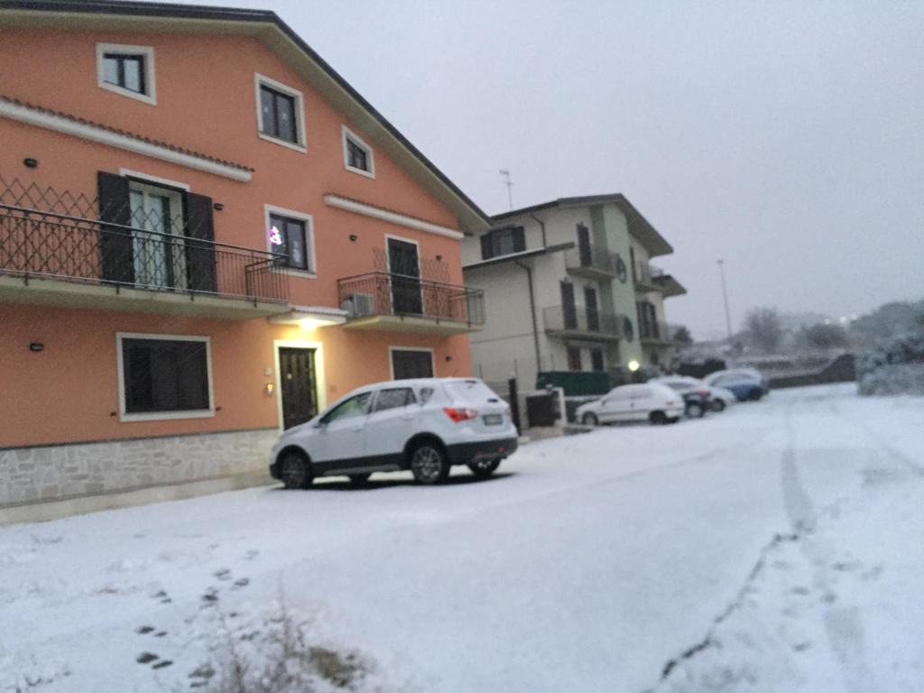 a car parked next to a building in the snow at La Luce del Sole in Belpasso