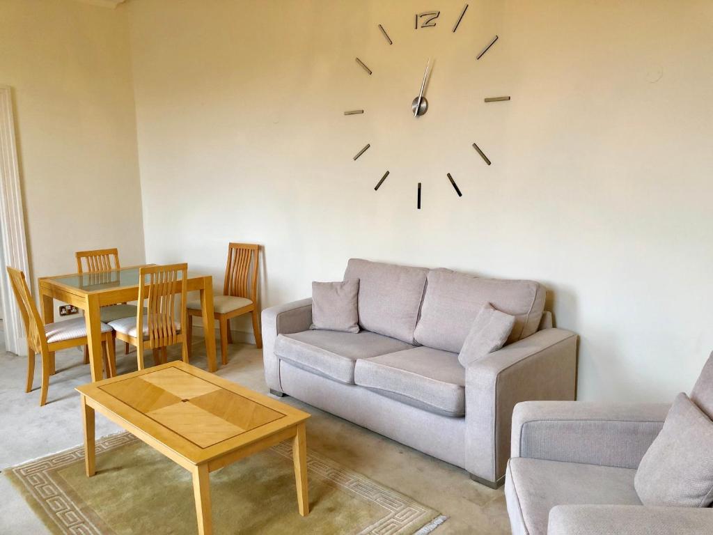 ein Wohnzimmer mit einem Sofa und einer Uhr an der Wand in der Unterkunft Buckingham Palace View Apartment in London