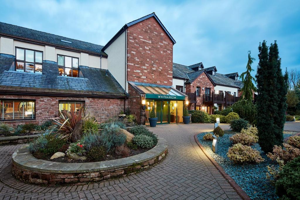 una casa de ladrillo con un jardín delante de ella en The Whitbarrow Hotel at Whitbarrow Village en Troutbeck