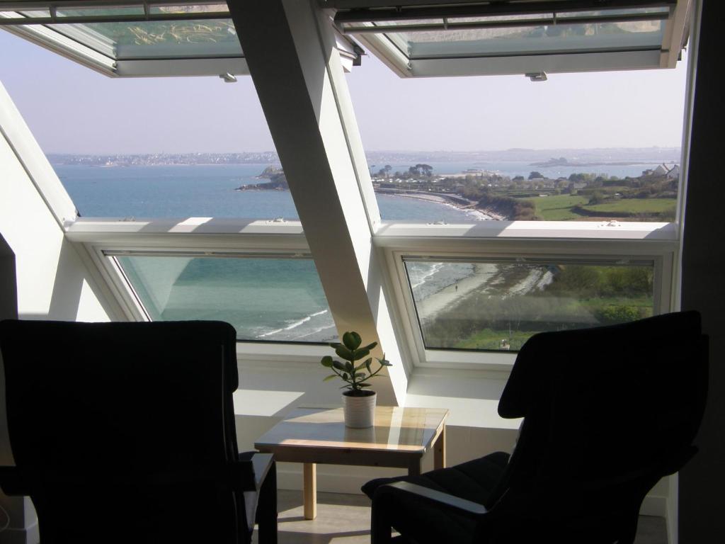 サン・ポル・ド・レオンにあるLocation Tromeal Lasalleの大きな窓のある客室で、椅子2脚とテーブル1台が備わります。