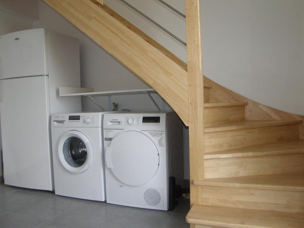 a laundry room with a washing machine and a staircase at Location Tromeal Lasalle in Saint-Pol-de-Léon