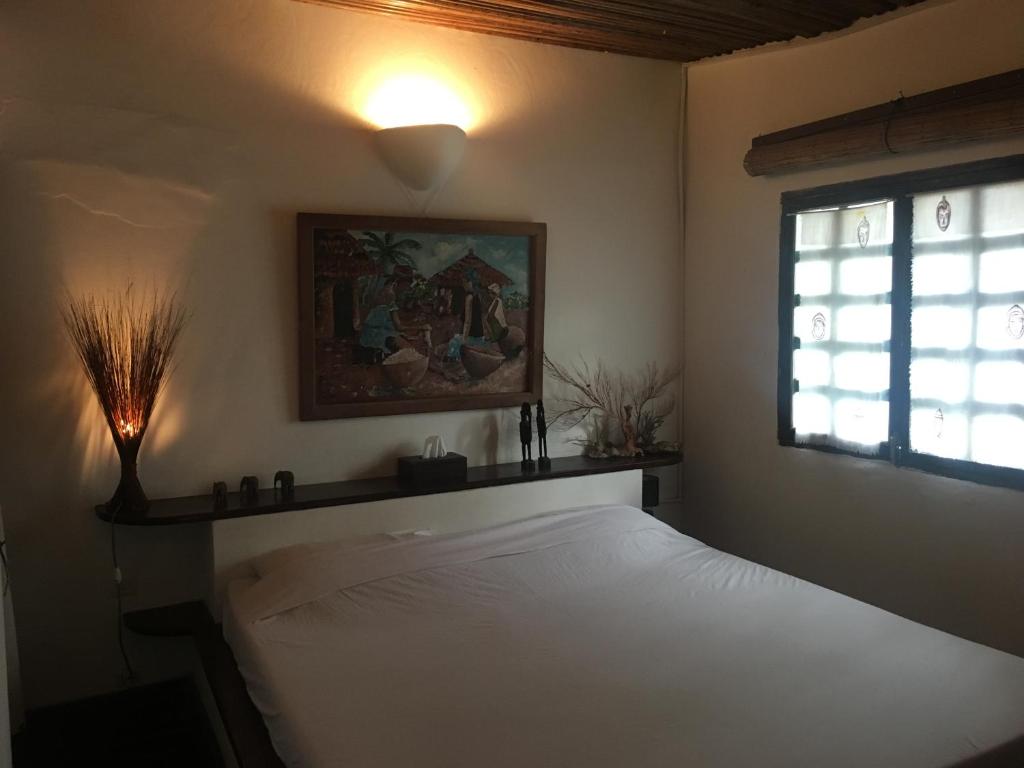 1 dormitorio con cama blanca y ventana en Hotel O Sole Mio, en Assinie