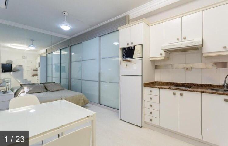 a kitchen with white cabinets and a bed in a room at Apartamentos Syria Las Canteras in Las Palmas de Gran Canaria