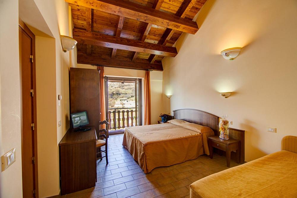 a bedroom with two beds and a television and a window at Ginepro d'Abruzzo in Casamaina