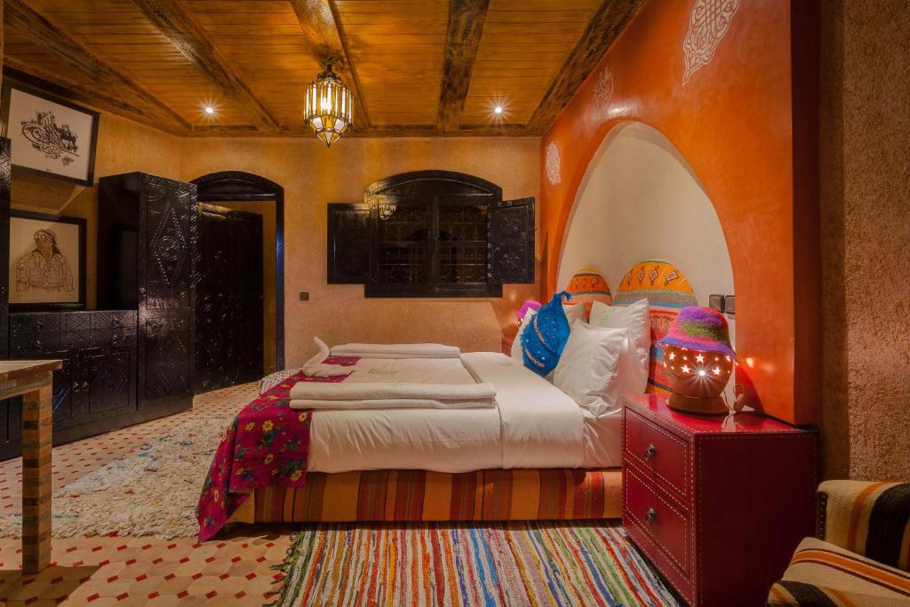 a bedroom with a large bed with an orange wall at Dar Ikalimo Ourika in Aghbalou