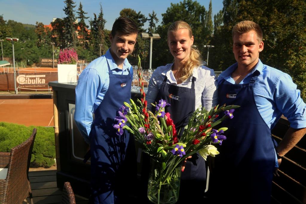 Drei Männer und eine Frau stehen neben einer Blumenvase in der Unterkunft Sport Pension Cibulka in Prag