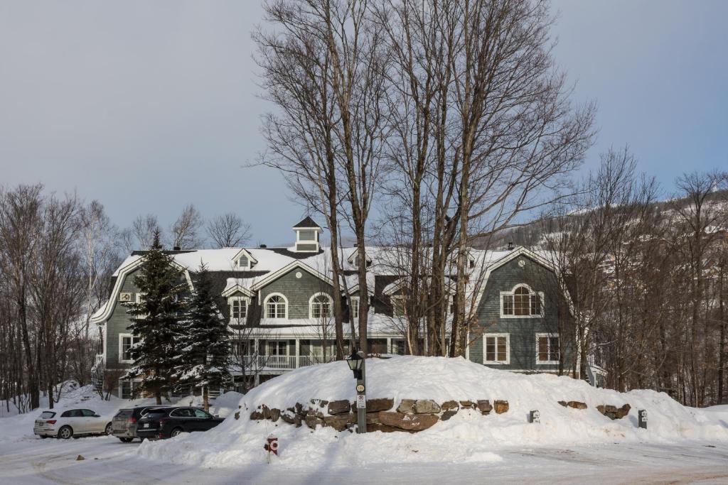 une grande maison avec de la neige devant elle dans l'établissement Les Manoirs by Rendez-Vous Mont-Tremblant, à Mont-Tremblant