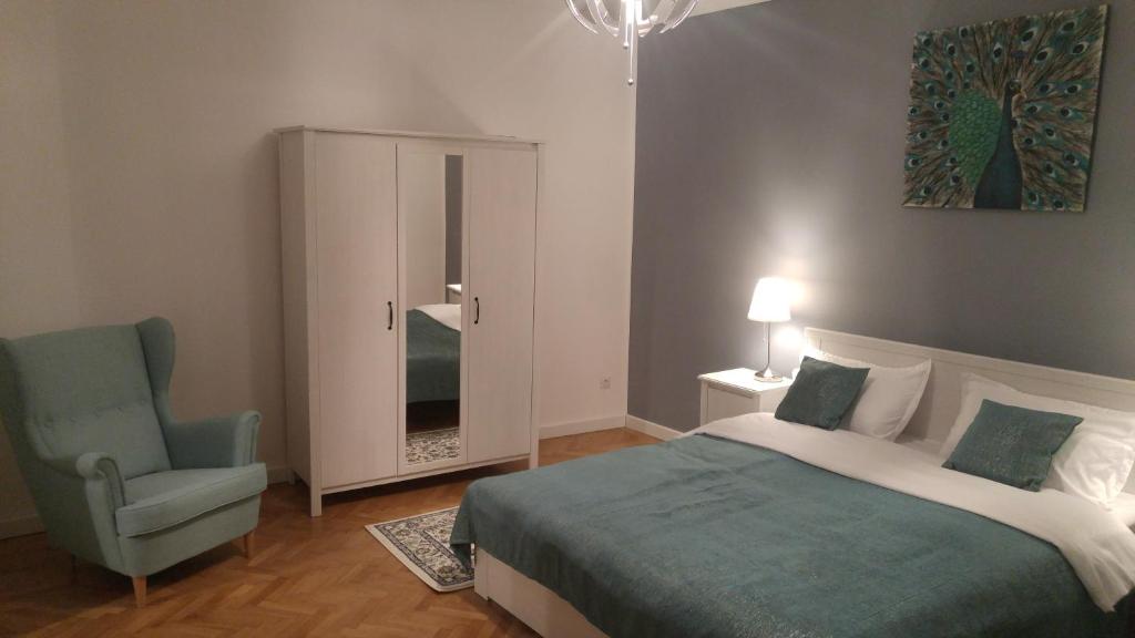 een slaapkamer met een bed, een stoel en een kast bij Apartment Bianco Central in Sibiu
