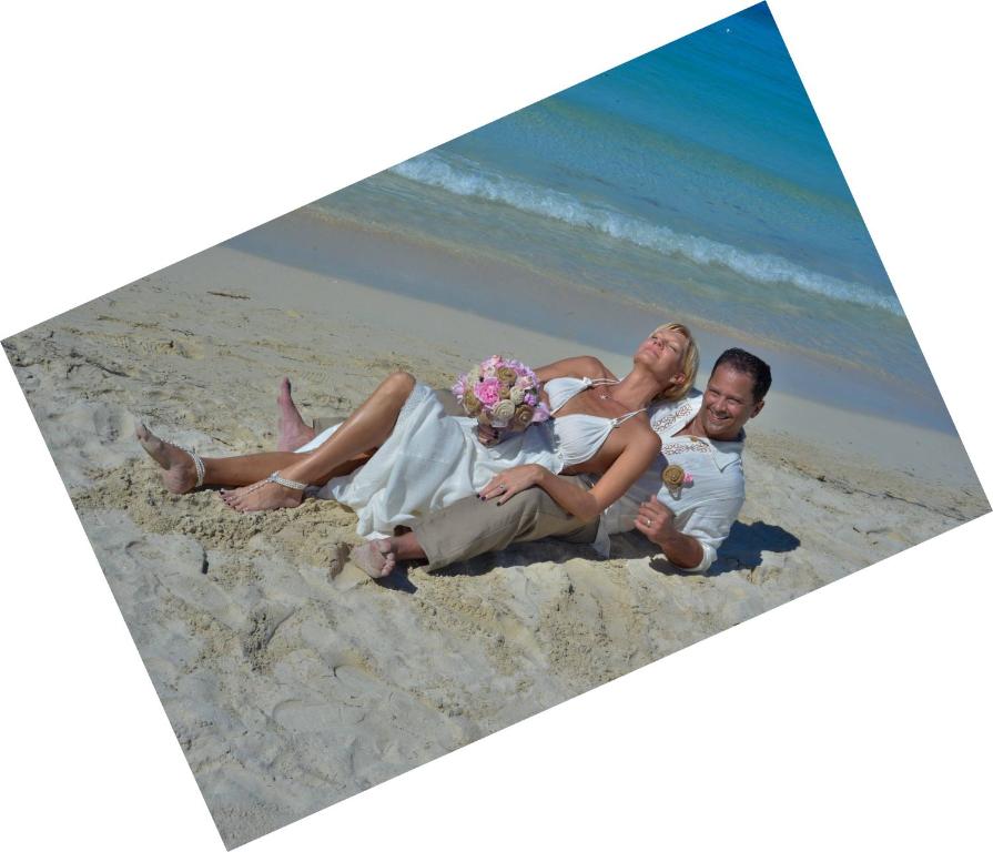 a bride and groom sitting on the beach at Coco La Palm in Negril