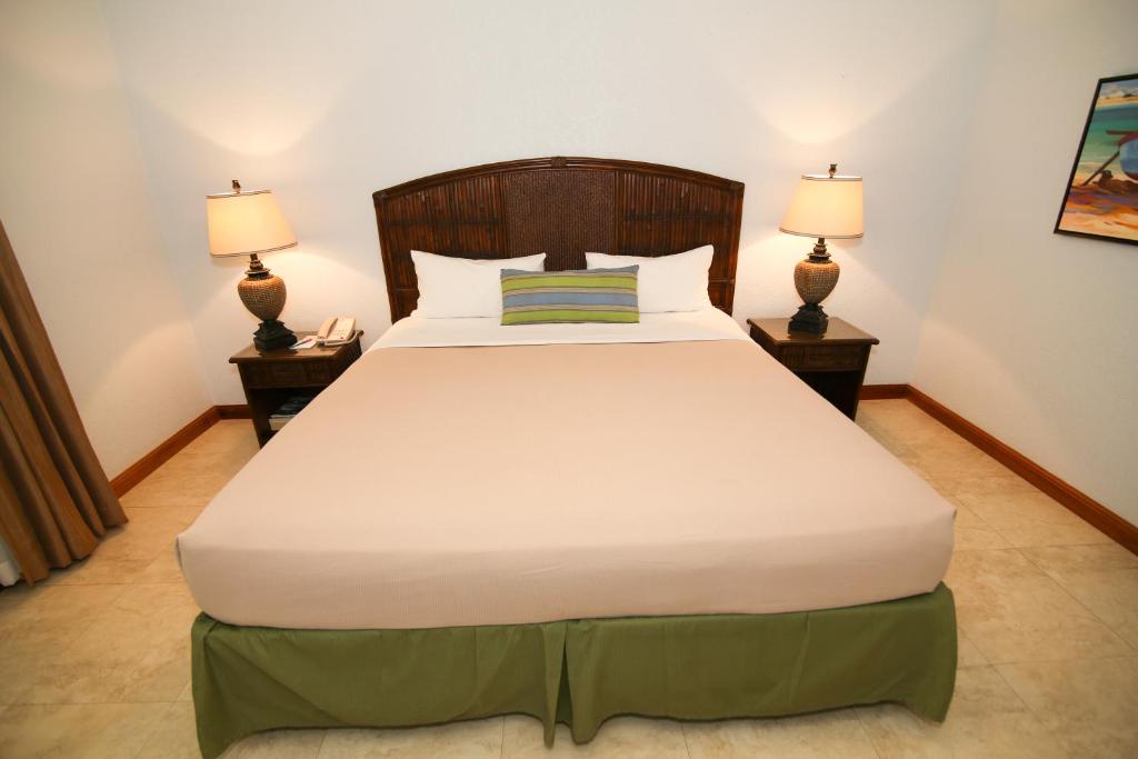 a bedroom with a large bed with two lamps at Coco La Palm in Negril