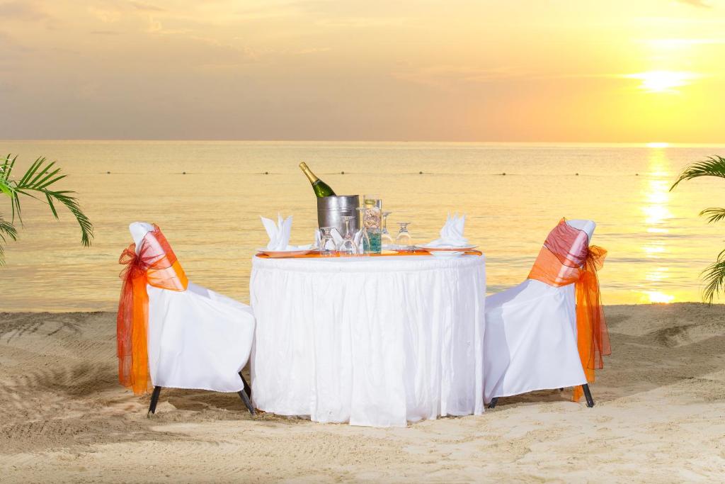 a table and chairs on the beach with the ocean at Coco La Palm in Negril