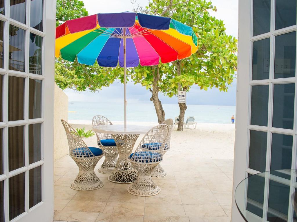 a patio with a table and a colorful umbrella at Coco La Palm in Negril