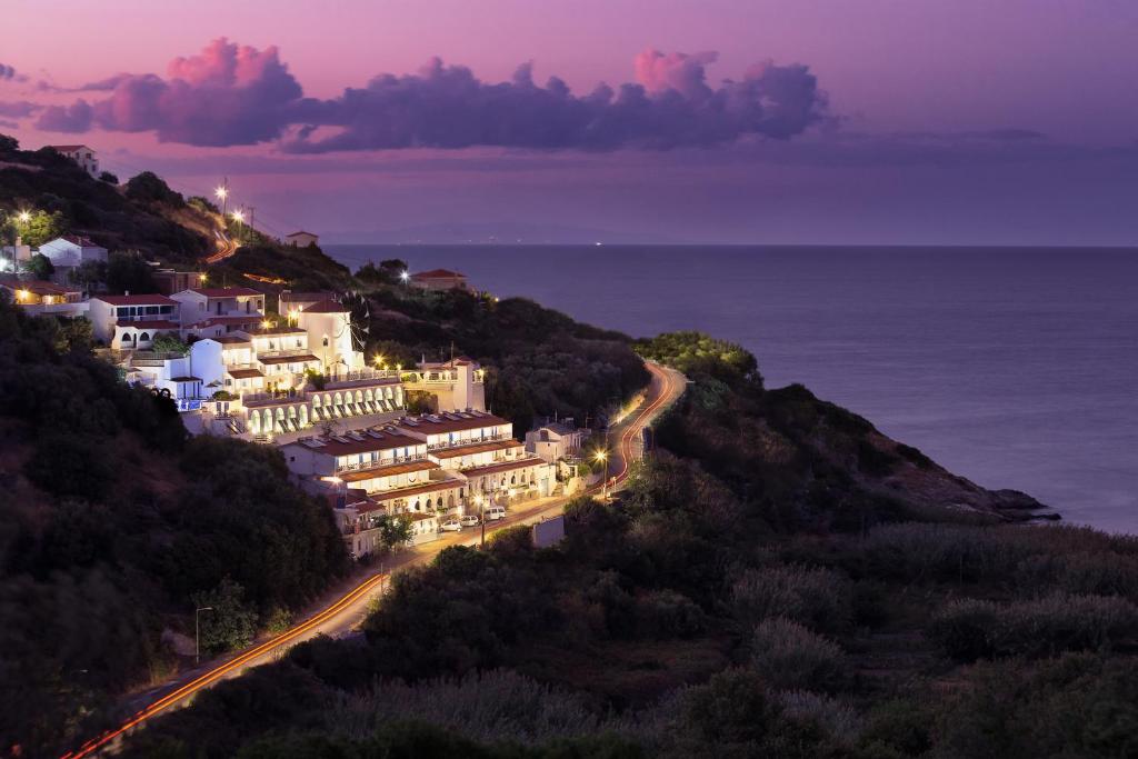 a town on a hill with the ocean at night at Kerame Studios & Apartments in Evdilos