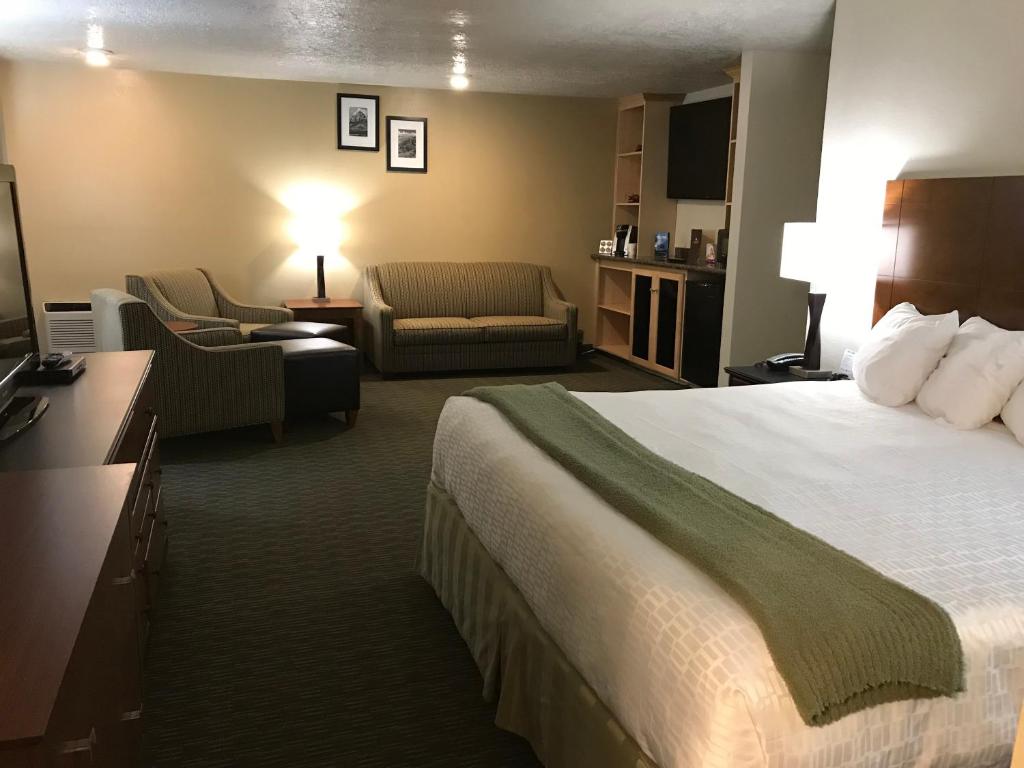 a hotel room with a large bed and a living room at Dinosaur Inn & Suites in Vernal