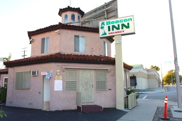 un panneau d'auberge au bacon devant un bâtiment rose dans l'établissement Beacon Motel, à Long Beach