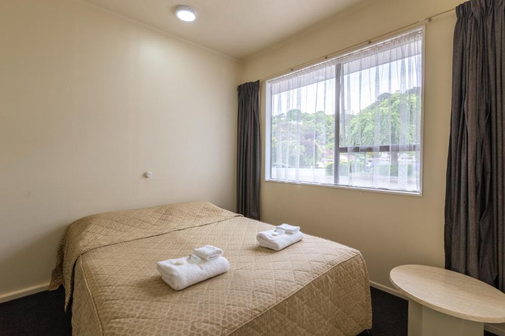 a bedroom with two towels on a bed with a window at Motel 22 in Lower Hutt