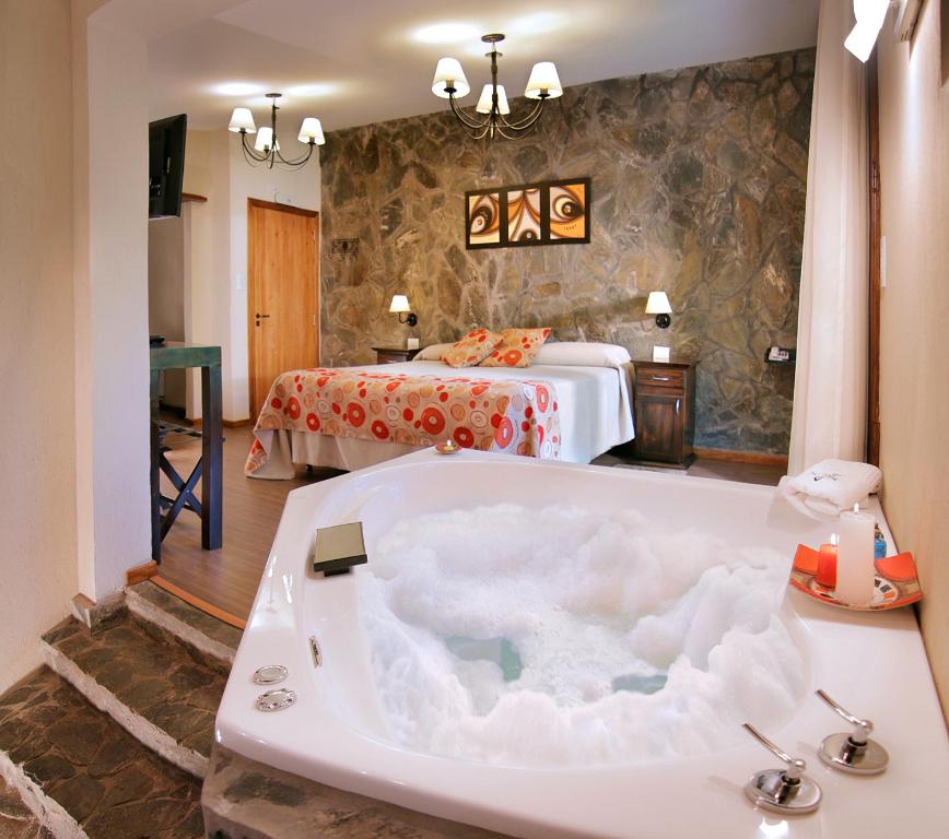 a bathroom with a tub in a room with a bed at Posada del Sauce in Villa General Belgrano