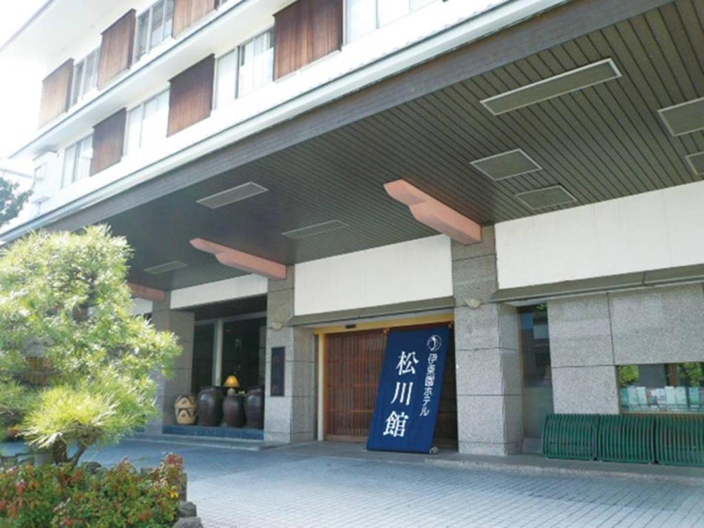 a building with a sign in front of it at Itoen Hotel Matsukawakan in Ito