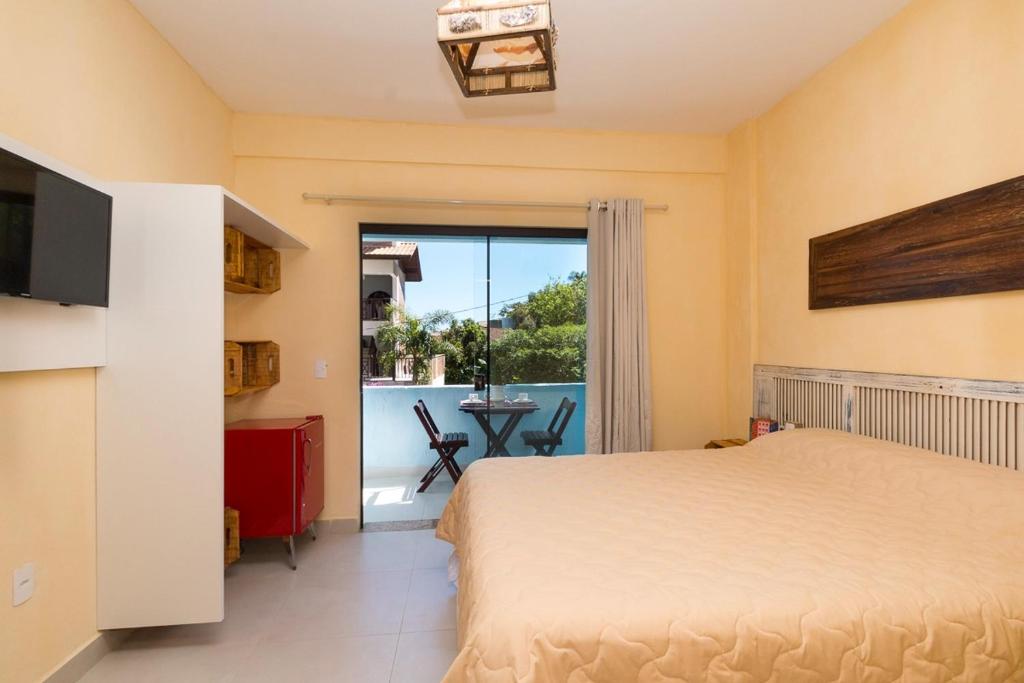 1 dormitorio con cama y vistas a un balcón en Vila Artesania, en Bombinhas