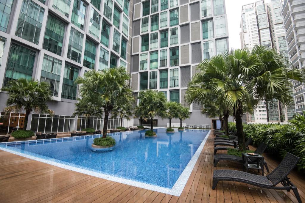 a swimming pool in the middle of a building with palm trees at Soho Suites @ KLCC by Luxury Suites Asia in Kuala Lumpur