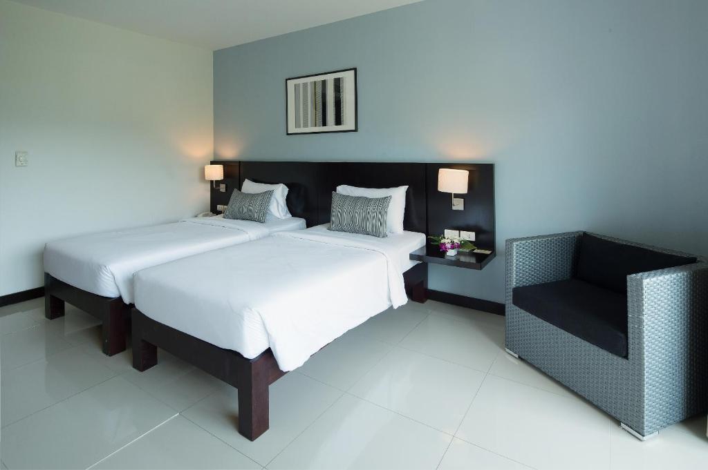 a bedroom with two beds and a chair in it at Simplitel in Karon Beach