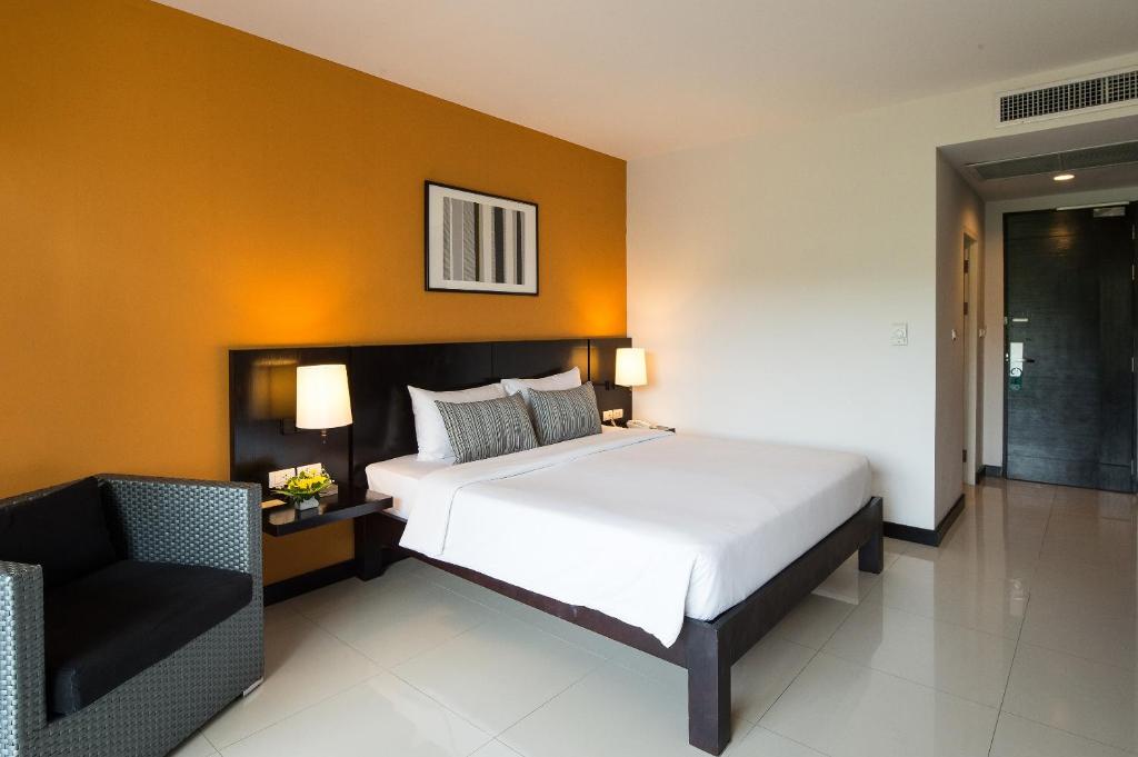 a bedroom with a large white bed and a chair at Simplitel in Karon Beach