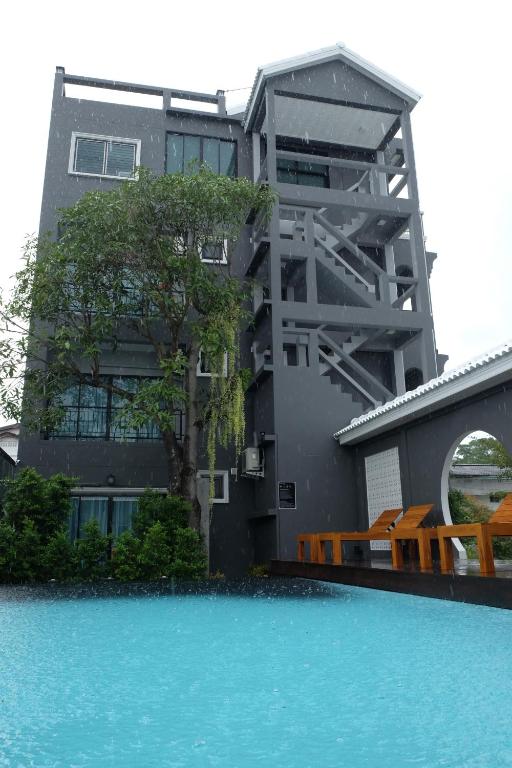 a building with a swimming pool in front of a house at The Besavana Phuket - SHA Extra Plus in Phuket Town