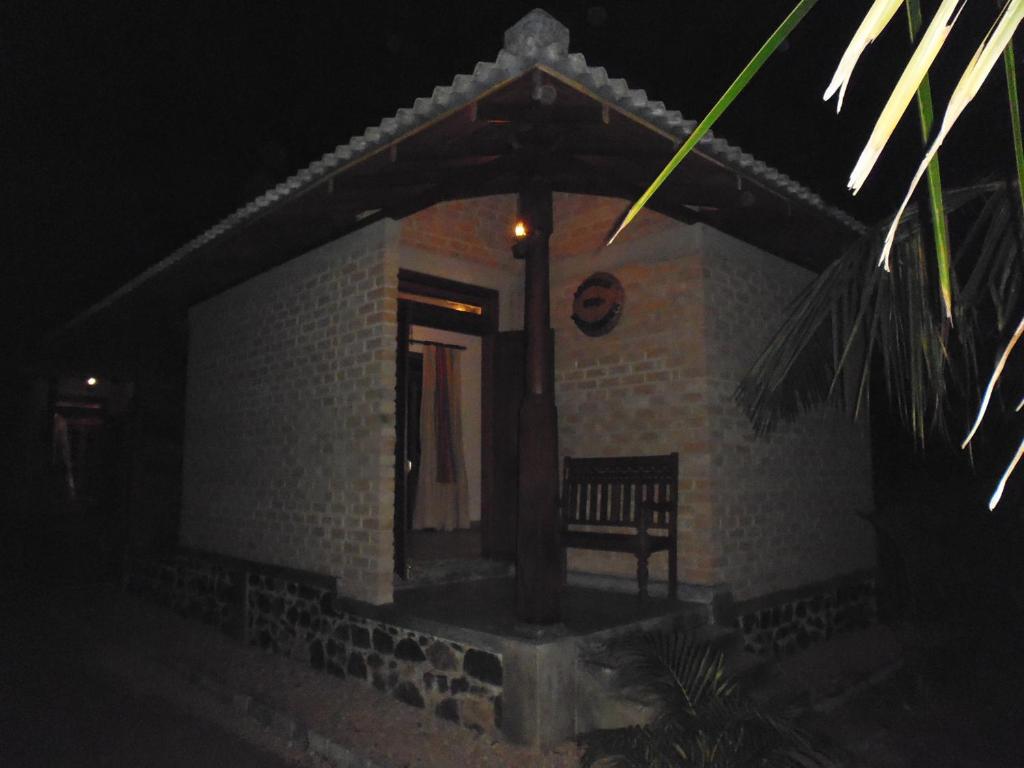 米瑞莎的住宿－Lanrich Eco Villas，一座小建筑,在晚上前面有长凳